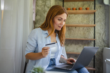 female hold credit card and use laptop for online shopping at home