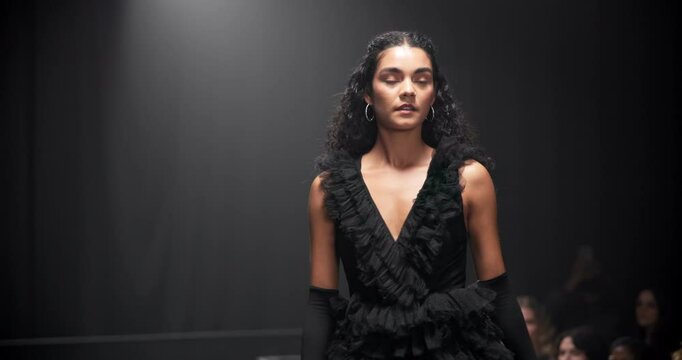 Fashion, walking and woman on runway for designer brand, creative clothes and outfit at showcase event. Audience, catwalk and model on a stage for couture collection, trendy style and luxury wardrobe