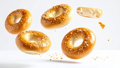 salted bagels floating in the air with crumbs against a clean white background