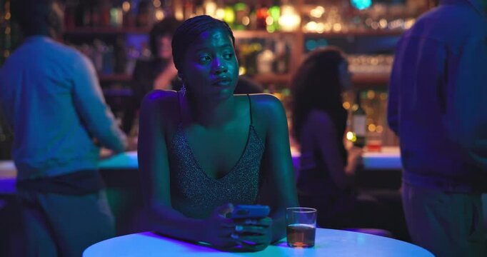Woman, phone and waiting in night club for date, texting and frustrated thinking with cocktail. Girl, person and sad with smartphone, alcohol or drink for meeting, disappointed and stood up at bar