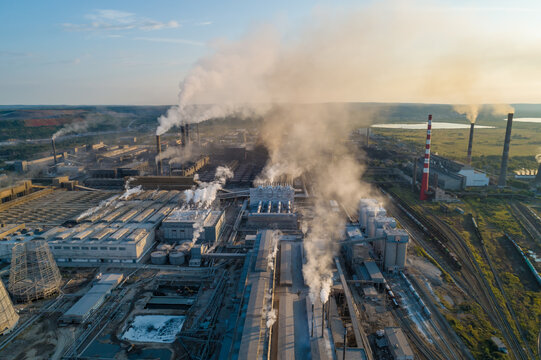 Air pollution from industrial facilities causes environmental concerns in urban areas during sunset hours.