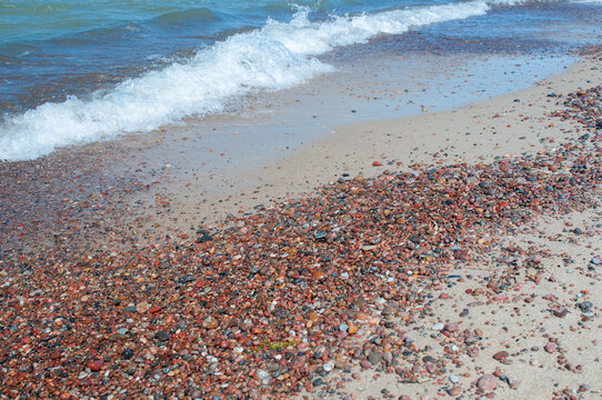 Fototapeta Pebbles and sand at seashore and sea waves
