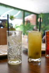  Iced drinks in tall glasses with straws on a restaurant table, featuring iced, citrus juice, and red punch, with cozy dining ambiance.