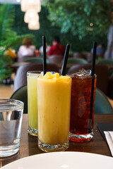 Iced drinks in tall glasses with straws on a restaurant table, with cozy dining ambiance.