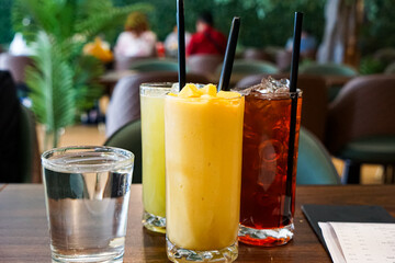 Iced drinks in tall glasses with straws on a restaurant table, with cozy dining ambiance.