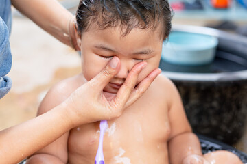 Shopping while mother helps daughter brush teeth in bathtub,Adorable baby girl taking a bath with...