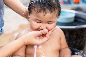 Shopping while mother helps daughter brush teeth in bathtub,Adorable baby girl taking a bath with...