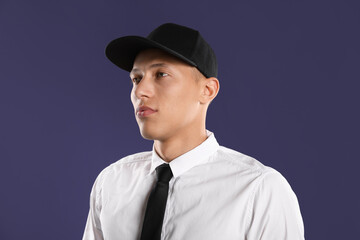 Young man in stylish baseball hat on dark blue background