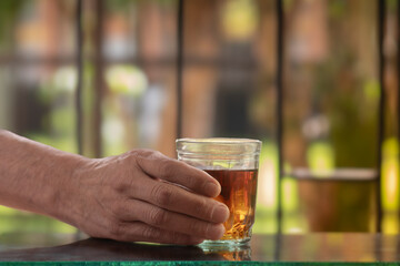 Glass of whiskey in male hands, blurred background