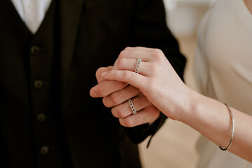 Caucasian young adult man and Caucasian young adult woman holding hands during wedding celebration,...