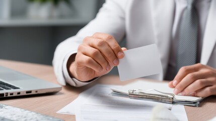 A man is holding a white business card in his hand