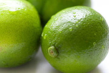 Fresh, vibrant green limes on a clean white surface. Juicy citrus fruits symbolizing summer freshness and healthy living. Selective focus creates a bright, inviting mood.