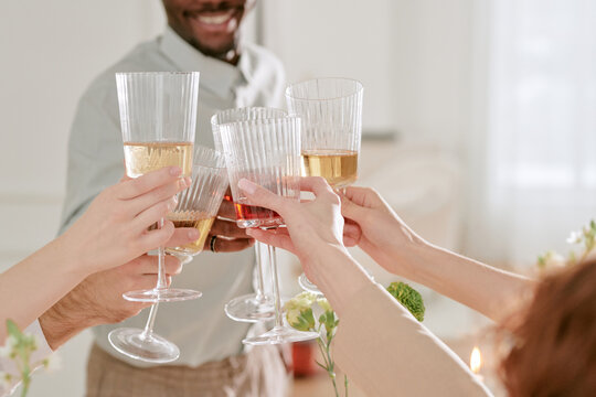 Group of young adult and middle aged people clinking glasses during wedding celebration, visible hands holding wine and champagne glasses in festive toast - Powered by Adobe