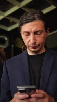 This footage conveys a focused and engaged mood, depicting a person intently looking down at their smartphone, ideal for illustrating digital communication, online work, or personal device usage