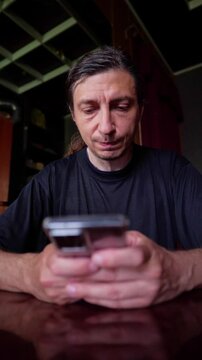 This footage conveys a pensive and concerned mood, depicting a person looking down at a smartphone with a hand near their face, suggesting a moment of serious contemplation