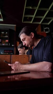 This footage conveys a focused and connected mood, depicting a person deeply absorbed in their smartphone, with a subtle reflection in the background adding depth