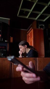 With a mood of profound concern or distress, the visual features a person with their hand on their head in the background, while a smartphone takes prominence in the foreground