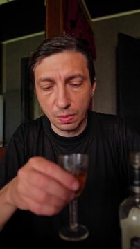 An intense and focused mood is captured as someone consumes a drink from a shot glass, suggesting a moment of indulgence, celebration, or a social gathering