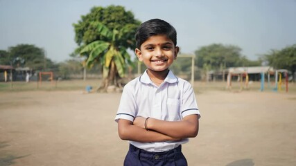 Confident and cheerful indian boy in school uniform standing with crossed arms in the schoolyard, showcasing a positive attitude towards education and school life