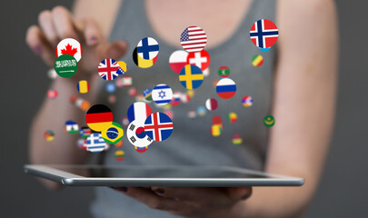 Image of a woman interacting with a tablet displaying flags of various countries, representing...