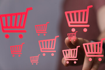 Person interacts with digital shopping carts, symbolizing online shopping and e-commerce.