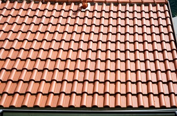 Close-up view of a neatly arranged terracotta roof with clay tiles. The uniform pattern and warm color provide a classic design, ideal for architectural and construction inspirations.
