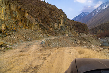 Dry dirt road winds through a rugged mountainous region, showcasing natural beauty of Kyrgyzstan