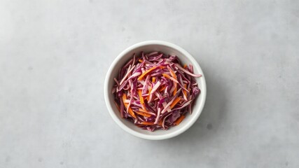 Fototapeta premium Freshly prepared coleslaw in a simple white bowl displayed on a minimalist grey surface, offering a healthy and colorful side dish