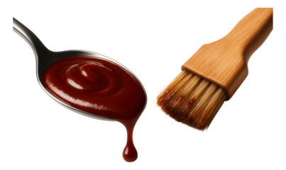 A silver spoon holding barbecue sauce with a drip next to a wooden basting brush, on transparent background.