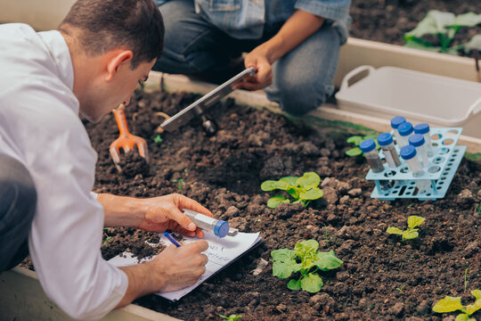 Multiracial students conducting farming and environmental research inside greenhouse laboratory.