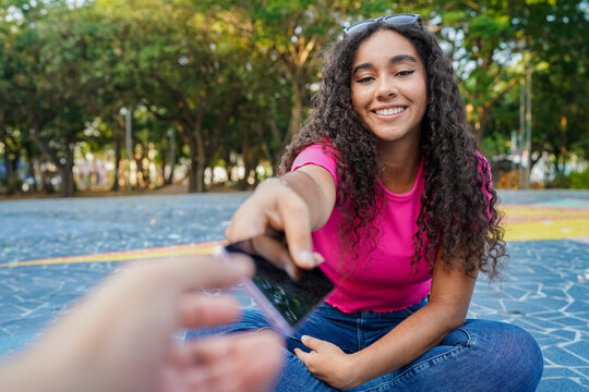 Young woman sharing her smartphone at the park