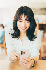 カフェでスマホを使う笑顔の女性
