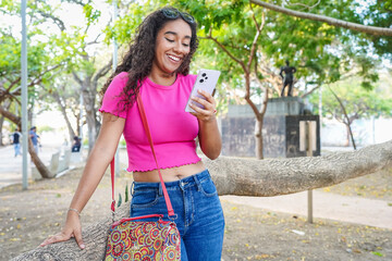 Young latin woman using mobile phone in a park in Guayaquil, Ecuador