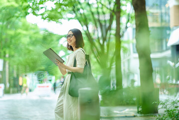 街角でタブレットPCを操作する女性