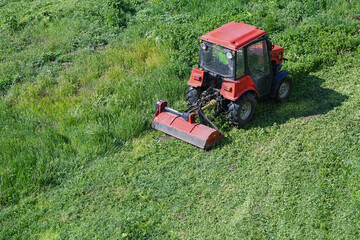 A red tractor drives across a green field, leaving a neat strip behind &mdash; an image of progress, work, and productivity. Perfect for business presentations in the agricultural sector.