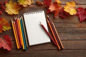 A cozy autumn scene with colorful leaves, pencils, and a notepad, perfect for back to school or creative projects, showcasing the warmth of the season and educational supplies.