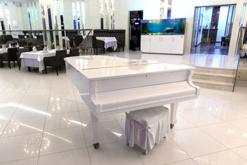 White grand piano in the center of the dance floor of a luxury restaurant