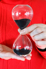 Woman holding a hourglass with time running out. Concept of life passing by.