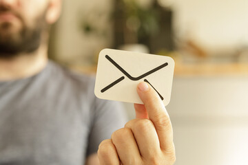 Close-up of a man holding a card with an email icon.  Communication, message, contact.