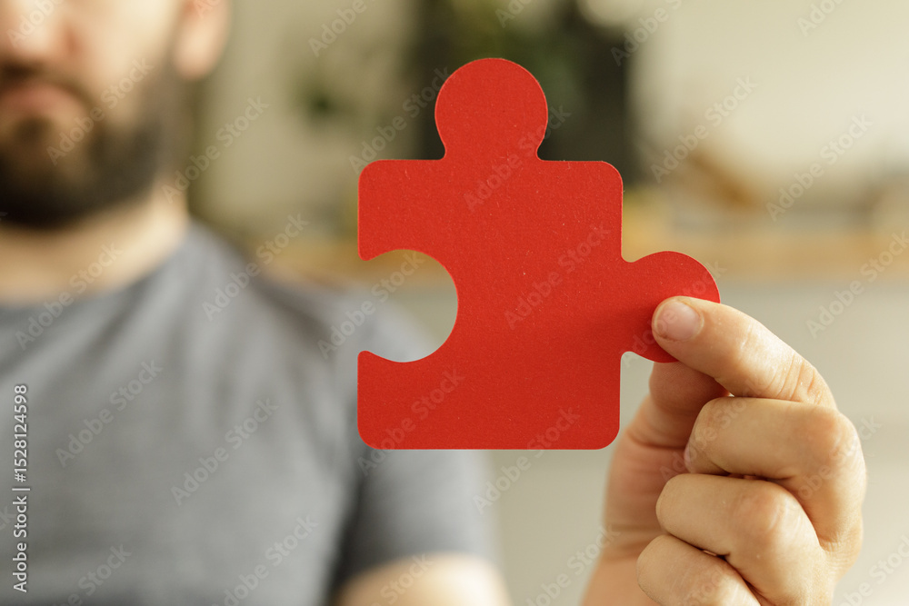 Poster a man holds a single red puzzle piece, symbolizing solutions, teamwork, and problem-solving.
