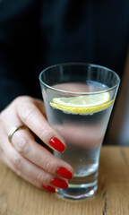 Woman drinking a glass of mineral water with a slice of lemon.