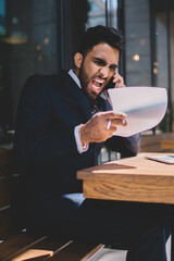 Conflicting businessman speaking on smartphone in cafe