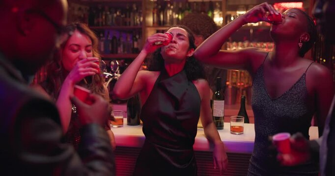 Excited people, night club and cheers with drink for party, celebration or toast together. Happy, group or friends with smile, alcohol or shots in late evening for good vibes, event or dance at bar