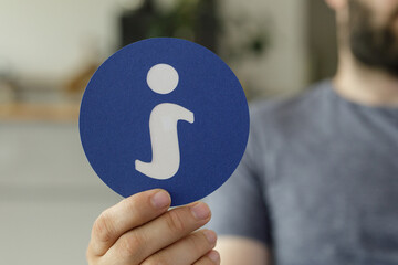 Hand holding a blue circle with a white information icon.  Useful for help, faq, support concepts.