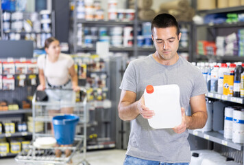 Interested experienced young handyman choosing quality paint primer for painting works in...