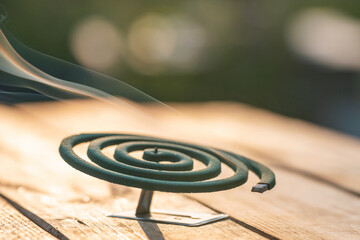 Smoldering mosquito coil in summer garden on wooden table, insect protection