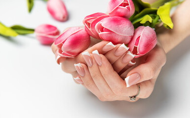 Woman holding pink tulips showing french manicure on white background