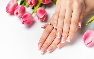 Woman showing french manicure and pink tulips on white background