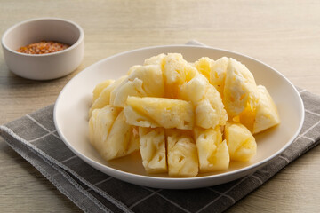 Ripe pineapple slice on white plate on a wooden table.