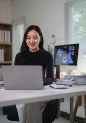 Young happy Asian businesswoman working with laptop computer in the office